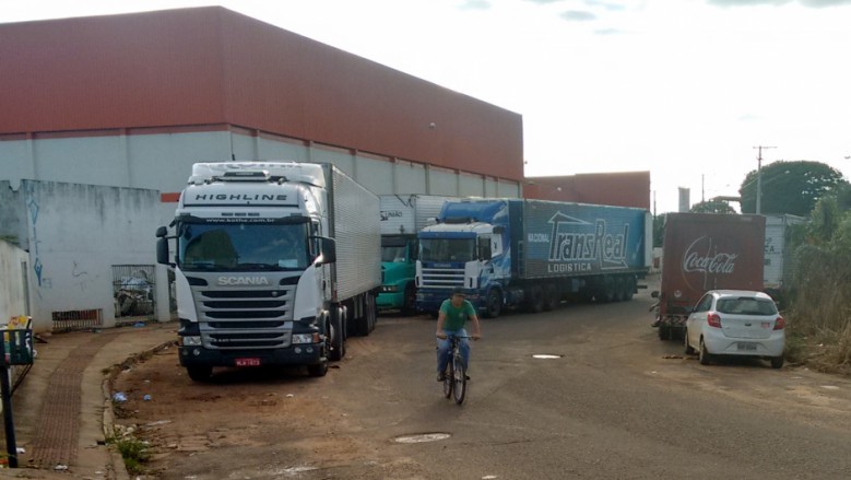 Caminhões estacionam para descarregar mercadorias e atrapalham trânsito na rua Uricuri.