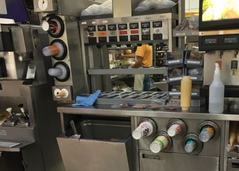 Funcionário manipula alimentos dentro de cozinha de fast food